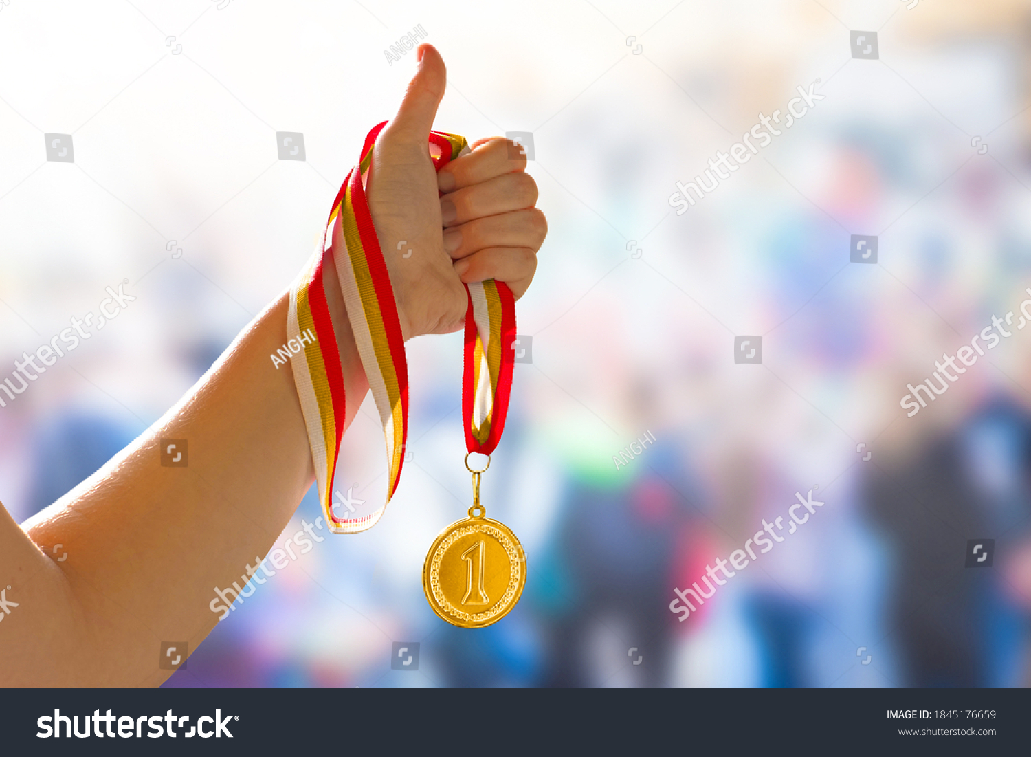 Woman hand raised with a thumb up sign  holding gold medal. Award and victory concept  copy space for text. First place in competition