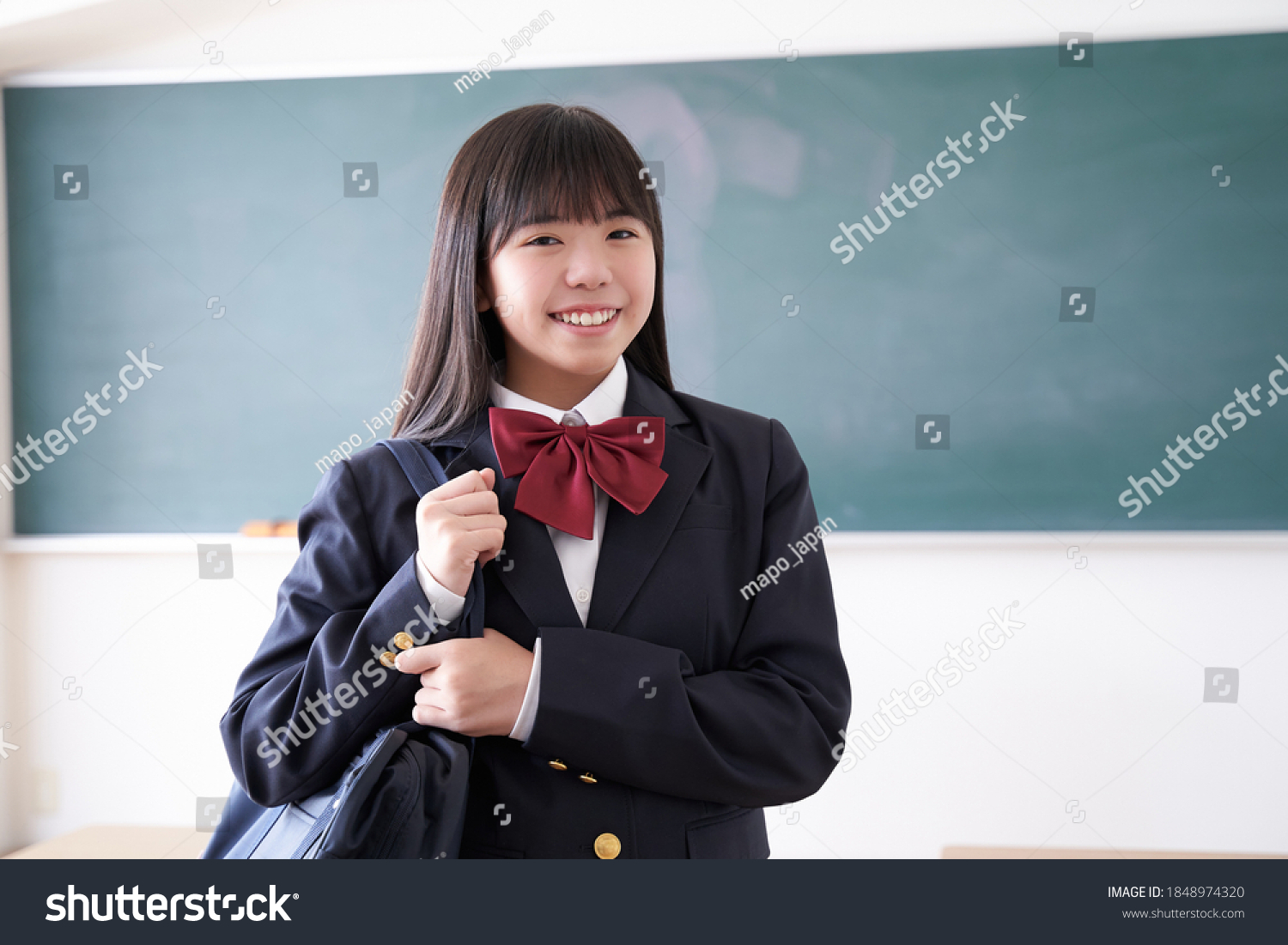 A Japanese junior high school girl holding her school bag in the classroom