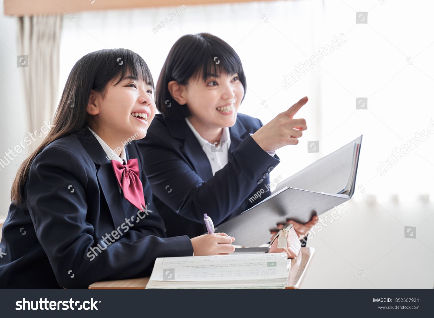 A Japanese junior high school girl is taught by her teacher in the classroom