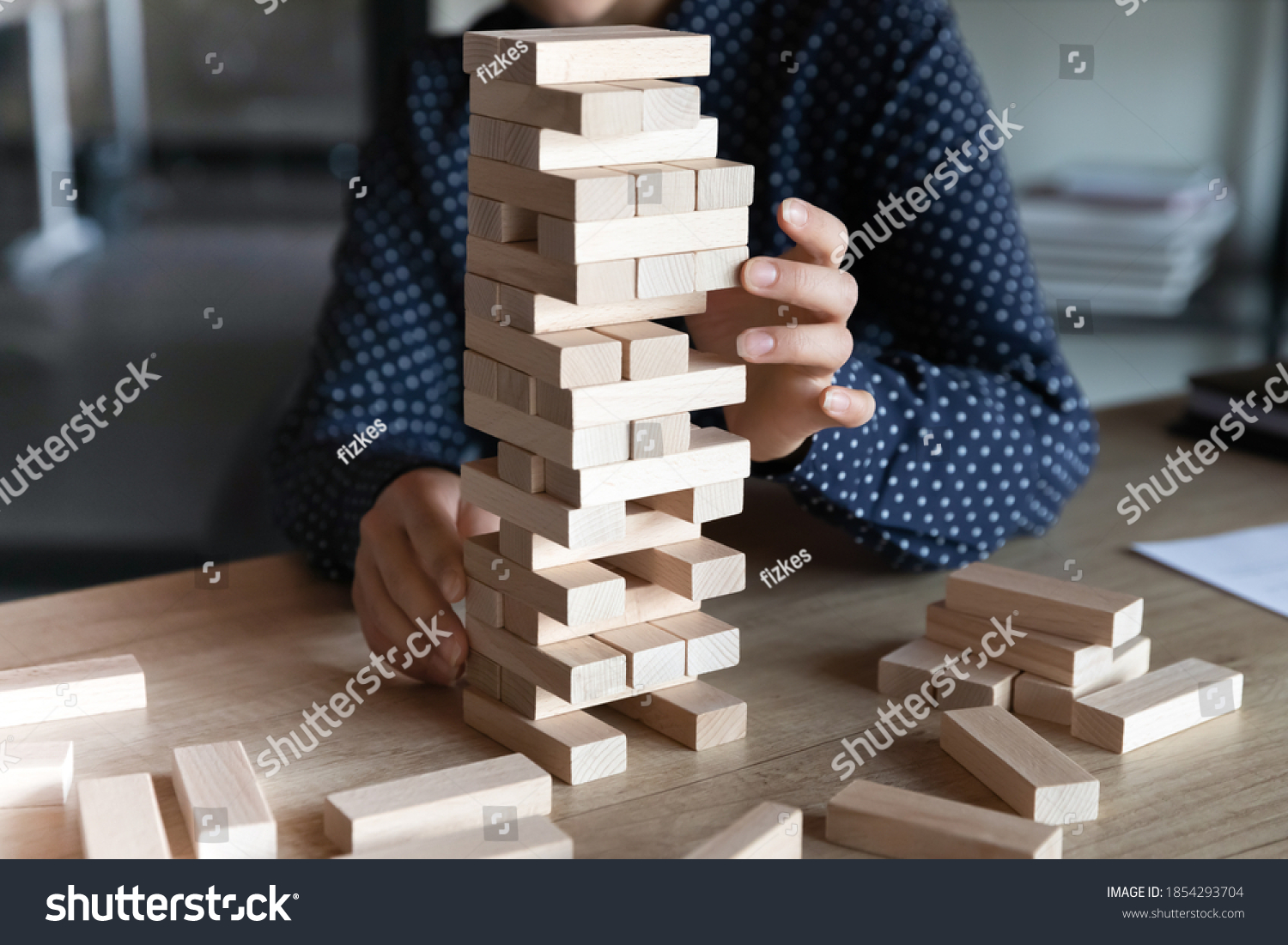 Close up Indian businesswoman building tower from wooden blocks in office  playing game  sitting at work table  employee planning future  developing project or business strategy  making decision