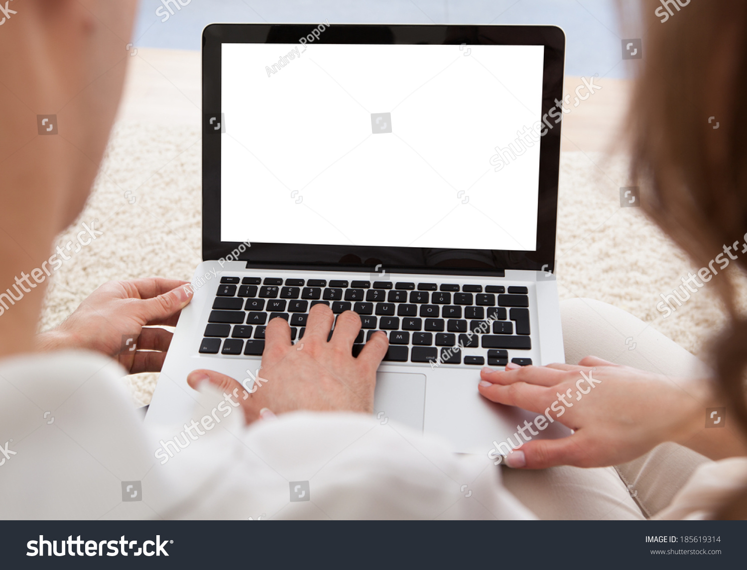 Beautiful young couple sitting side by side on a sofa looking at a laptop together