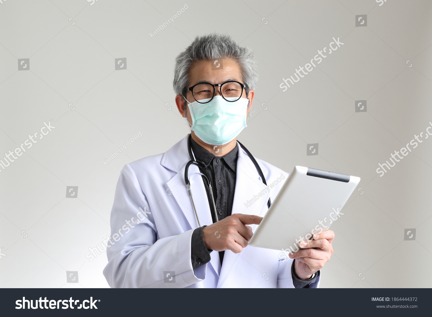 The senior Asian physician with mask on the white background.