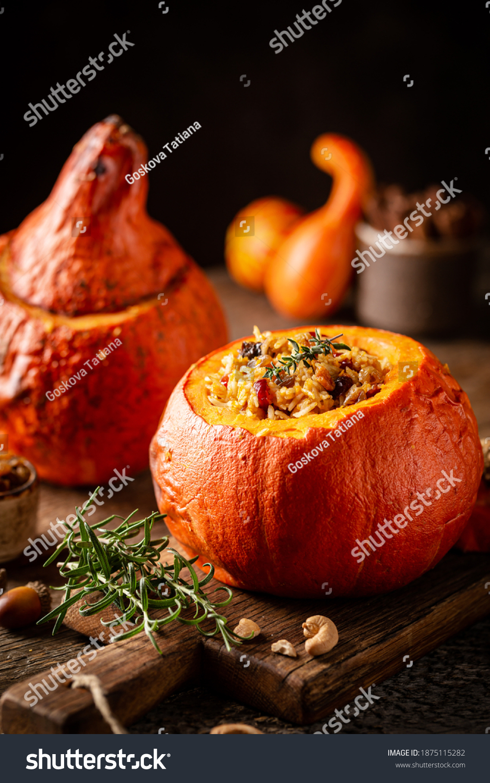 Tasty baked pumpkin stuffed with rice  vegetables  cashews and dried fruits on wooden table with dark background