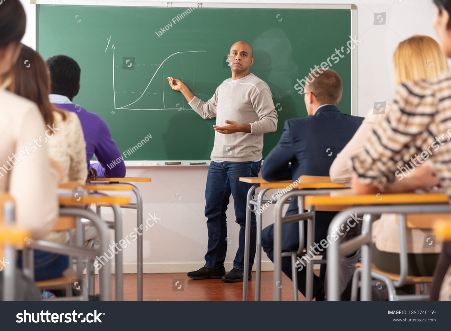 hispanic teacher standing near chalkboard