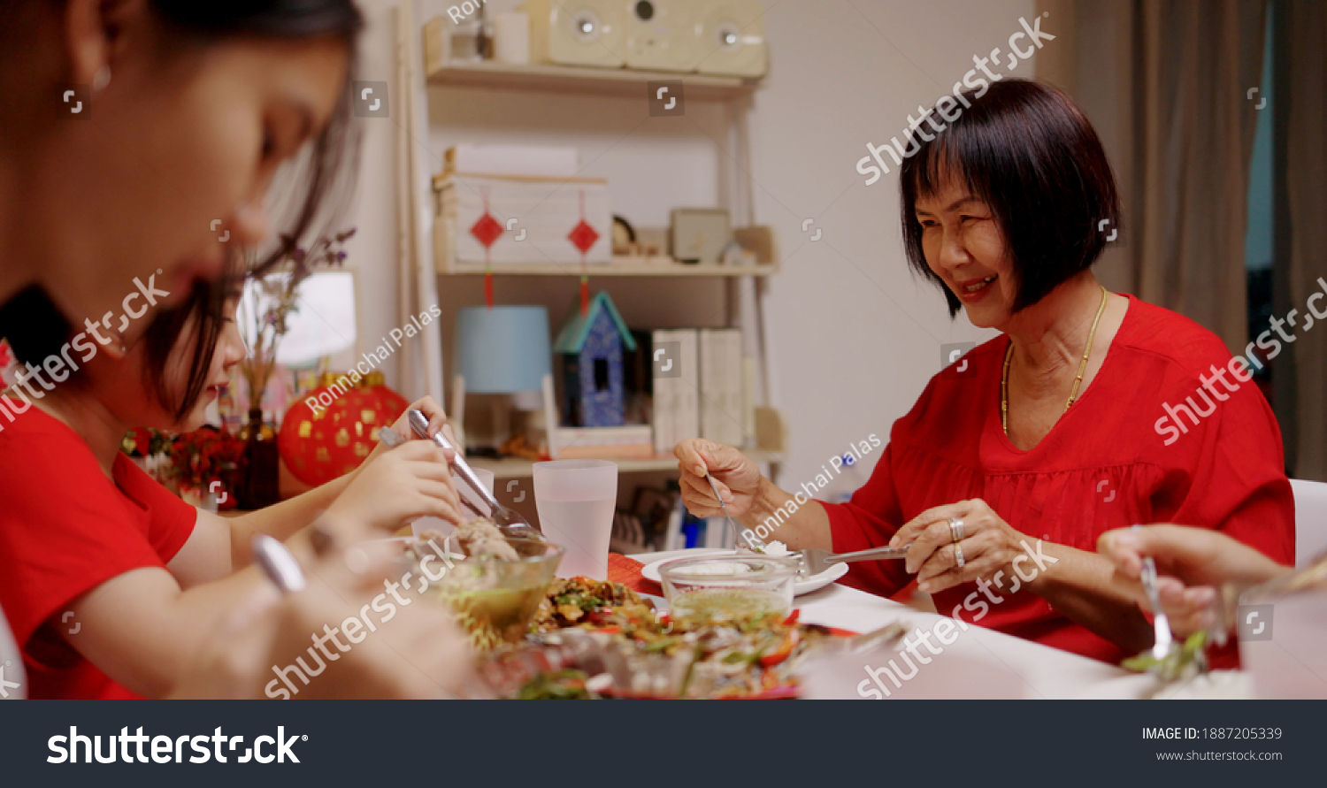 Happy Chinese Family Eating Dinner For Chinese New Year Celebrations Together At Home.