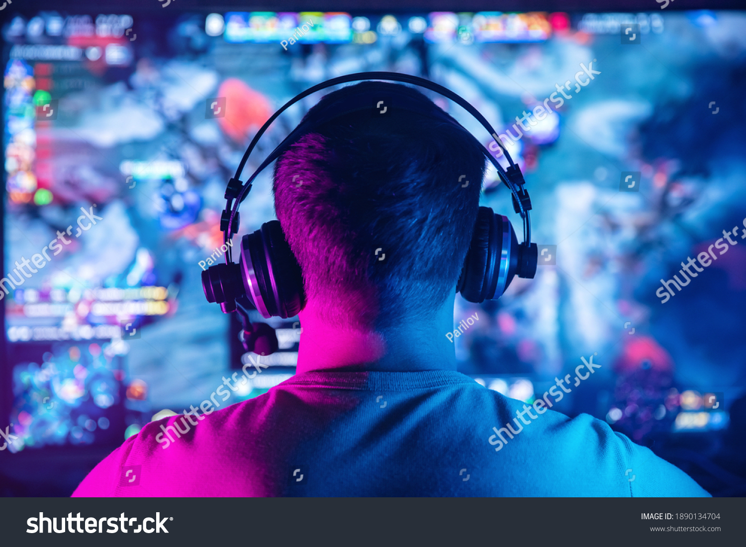 Professional cyber gamer studio room with personal computer for stream in neon color blur background. Back view soft focus.