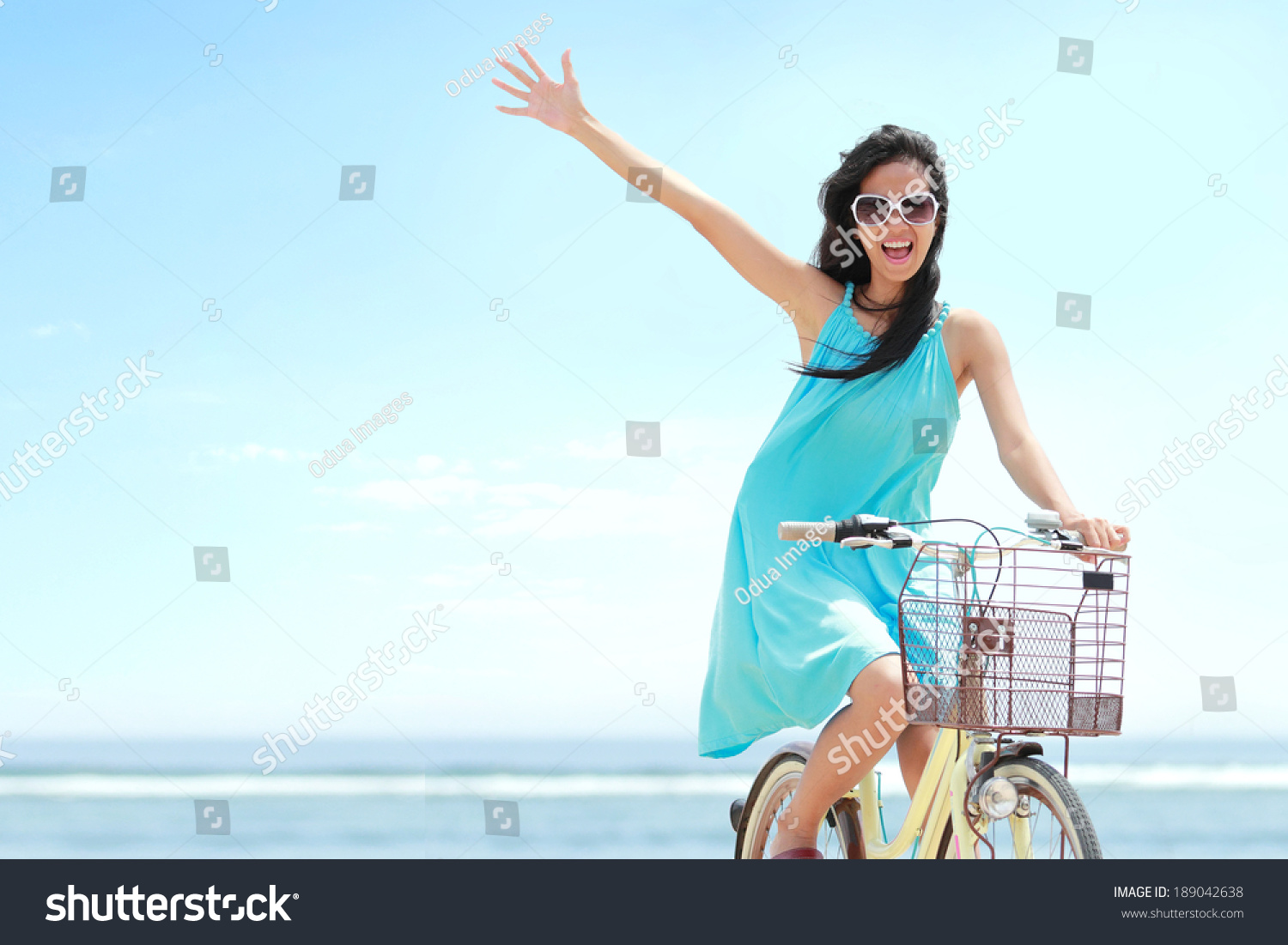carefree woman having fun and smiling riding bicycle at the beach