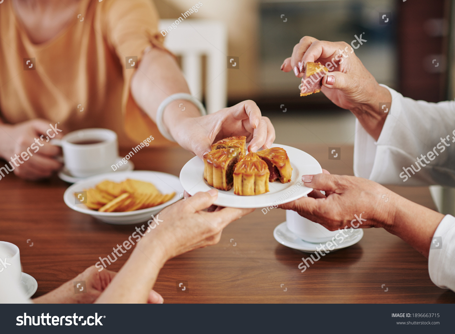高级妇女的手在家里庆祝中秋季音乐节时吃美味的传统月球蛋糕