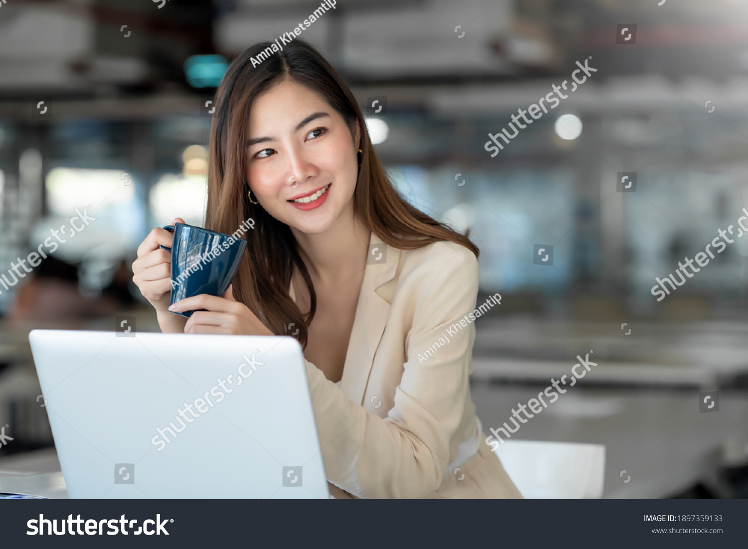 Asian business women sit in the office and drink coffee look laptop computer 