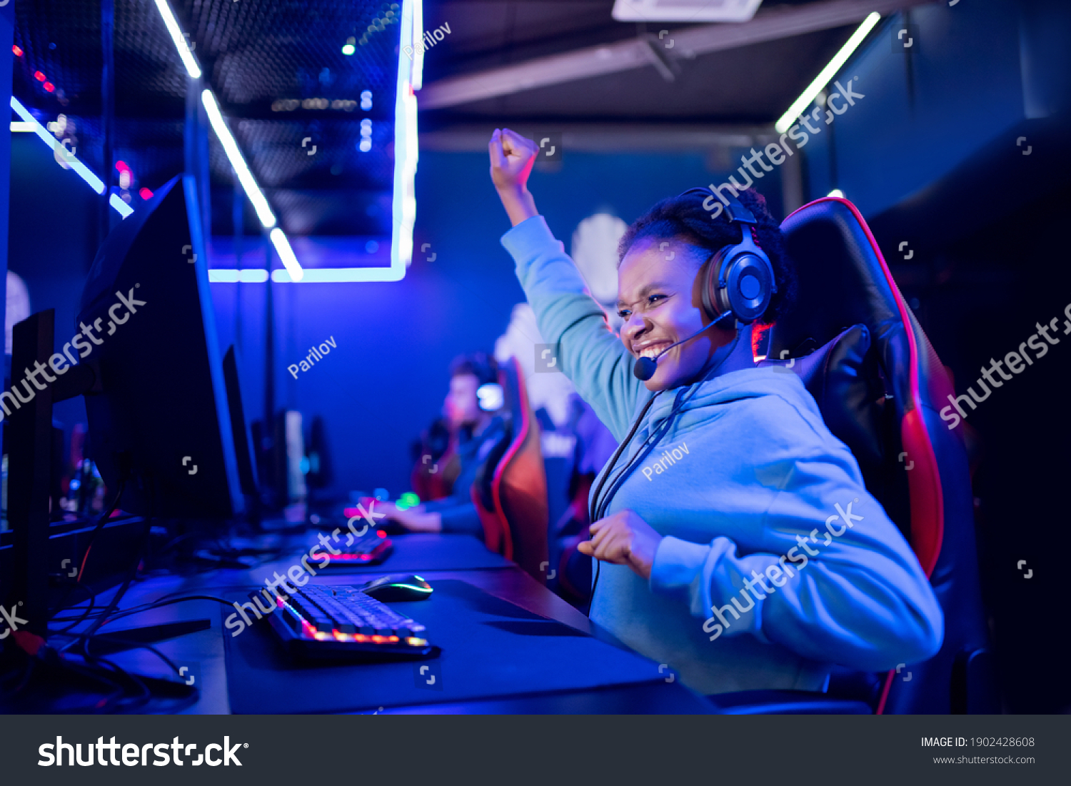 Streamer african young woman rejoices in victory professional gamer playing online games computer with headphones  neon color.