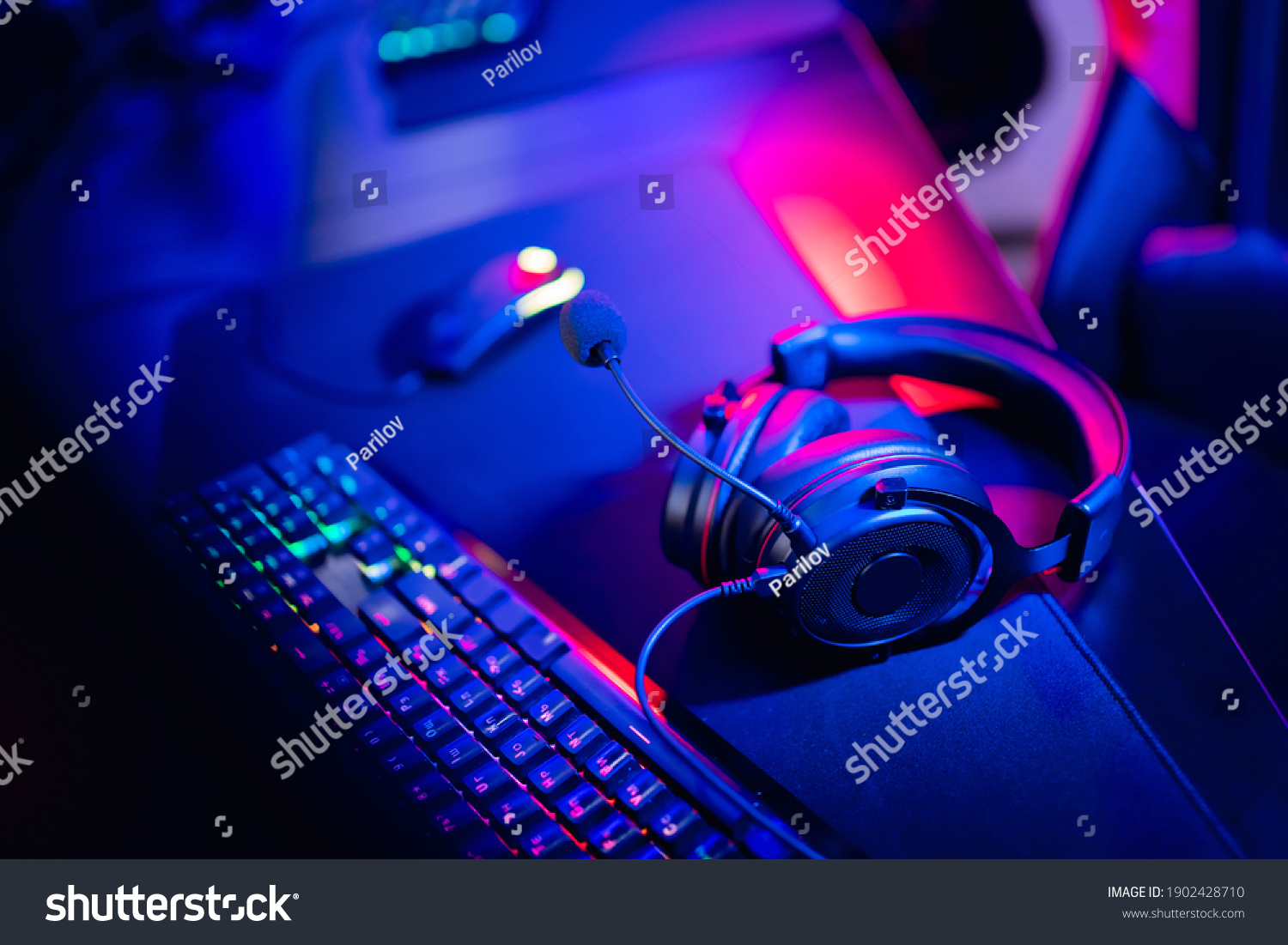 Professional gamers room with headphones microphone for cyber esports and video games on neon background of gaming monitor.