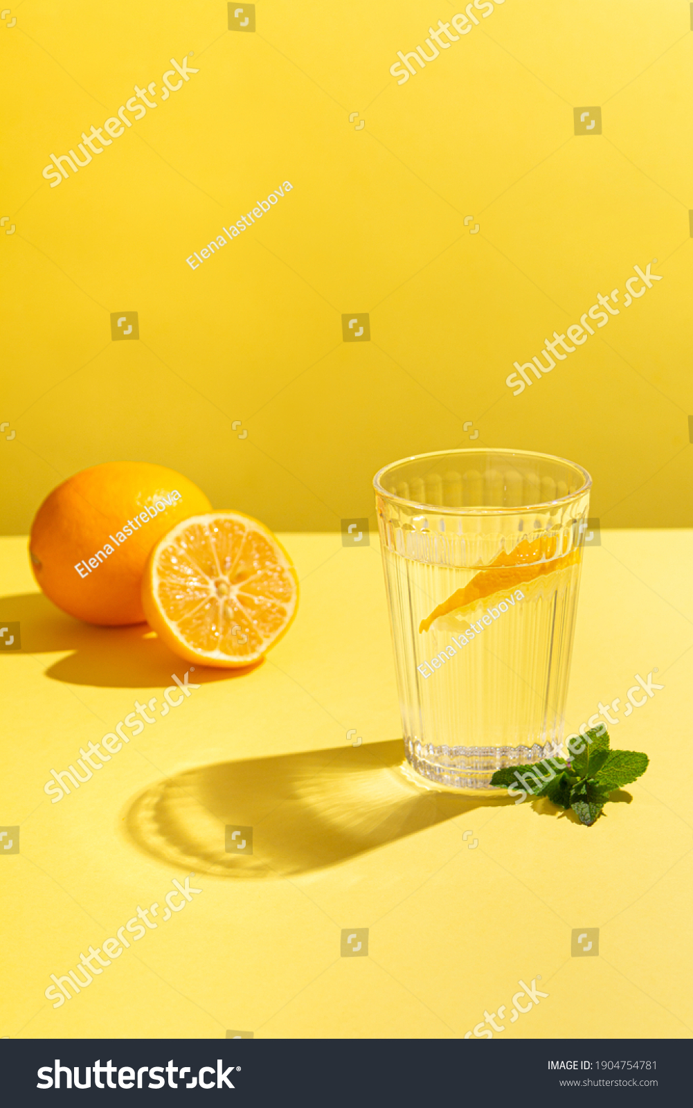 Fresh still water on a yellow background with lemon and mint