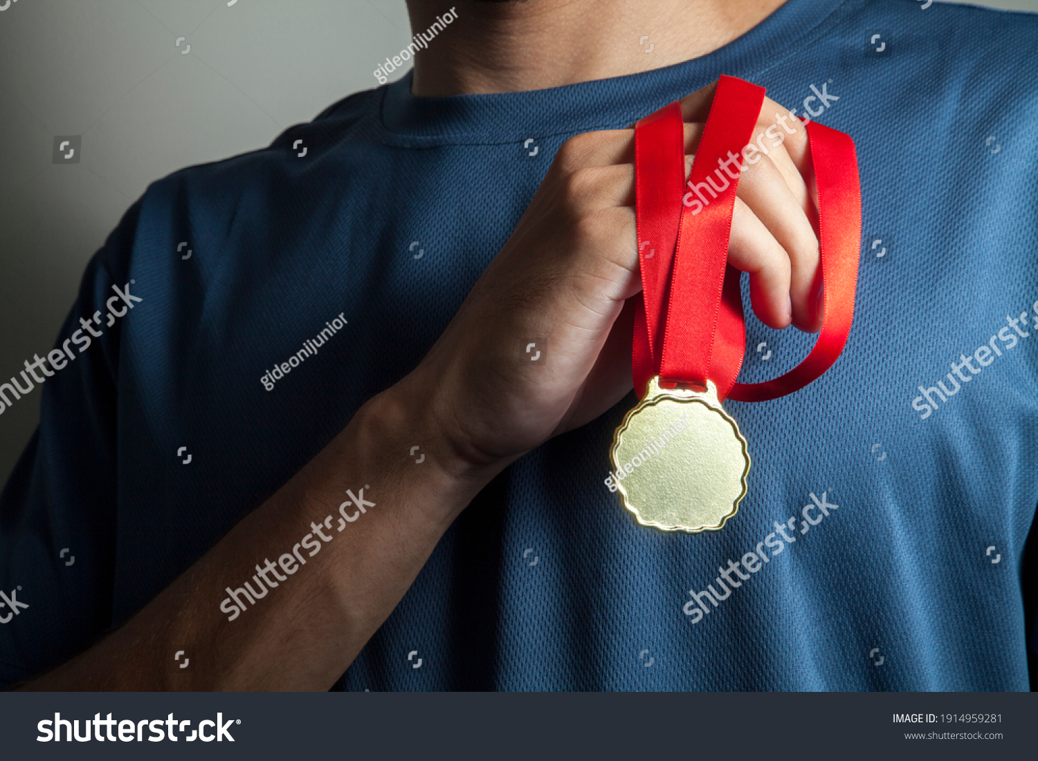Man holding gold medal with hands at chest height and with a neutral bottom.  Award concept.