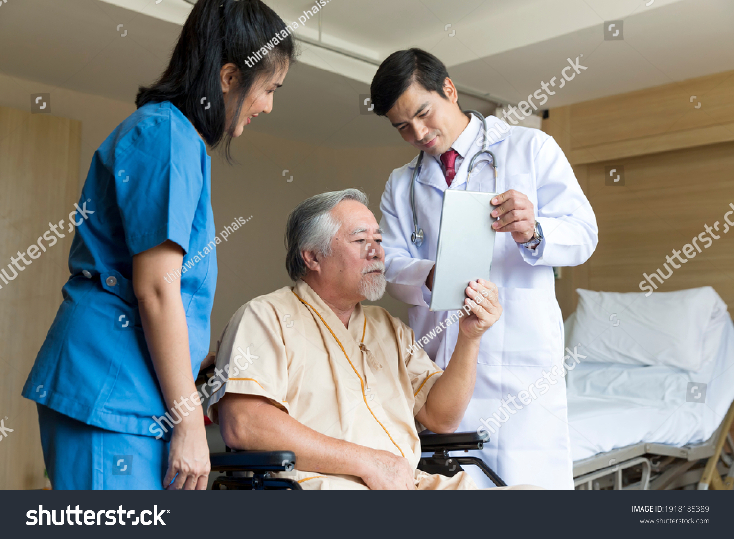 Doctors and physical therapists are caring for elderly sick people. Doctor and nurse taking care of elderly patient at hospital room. elderly patient using tablet.