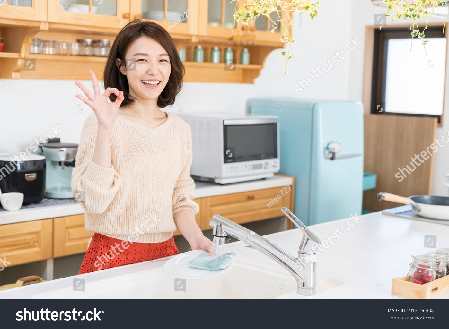 young attractive asian woman washing the dishes in a kitchen
