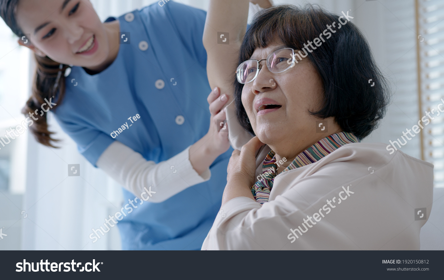 Young senior asia citizen female with scrubs nurse physiotherapy worker at home in rehabilitation therapy service for aging parents. Massage for older care ache pain joints exercise in old people.