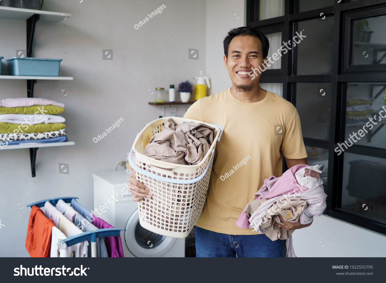 Housework. asian Man doing laundry at home loading clothes into washing machine