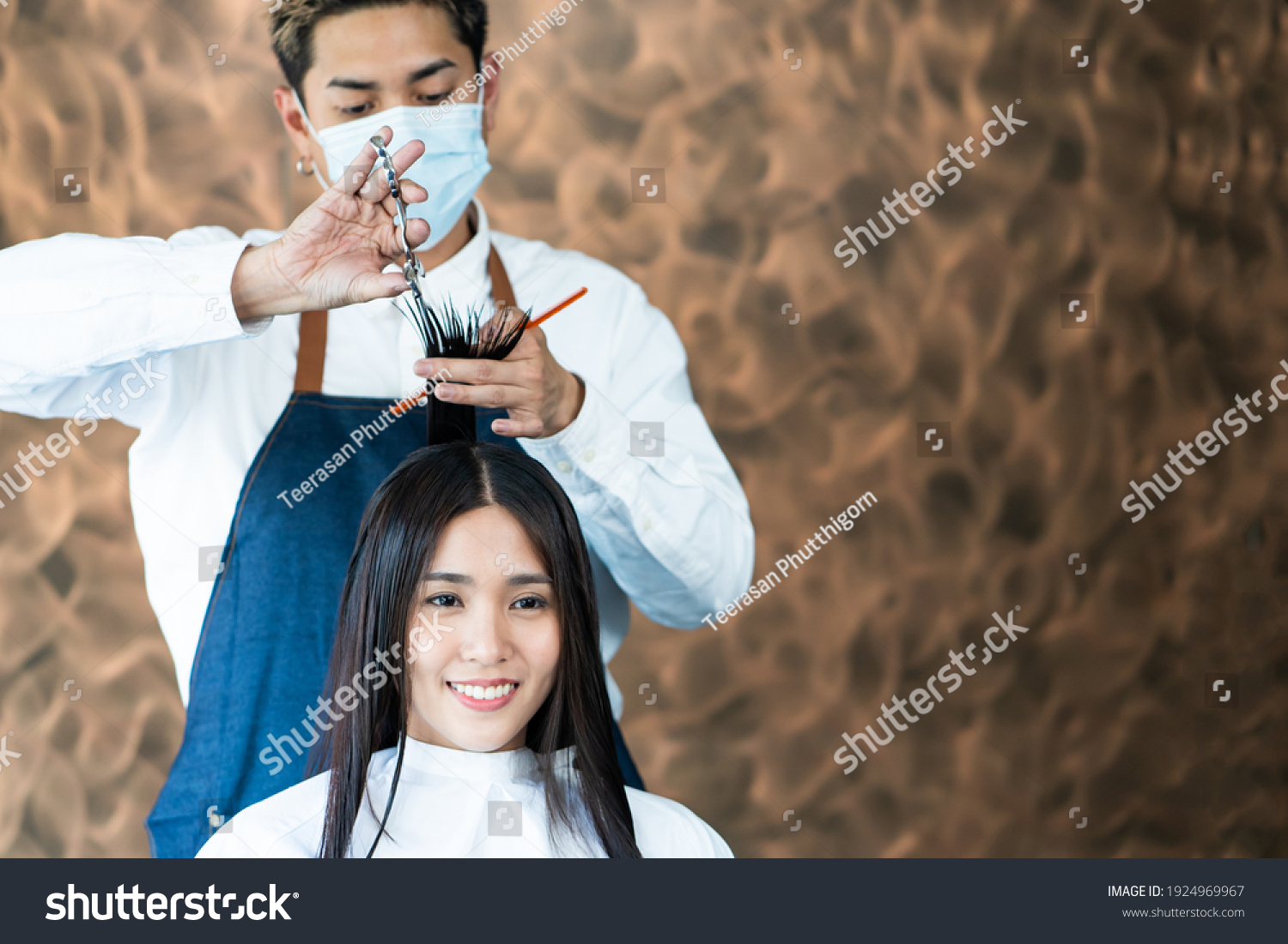 Selective focus at face of Asian women with Hair stylish while do hair cut and wearing surgical face mask while styling hair for client. Professional occupation  beauty and fashion service new normal