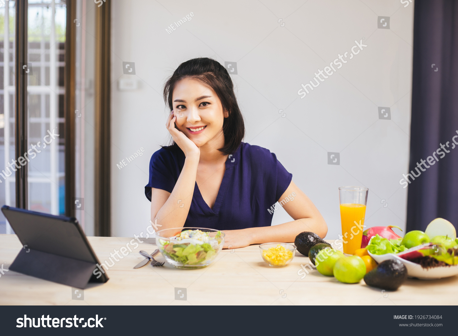 Happy Asian woman vegetarian healthy eating salad food and use tablet on the table. Young woman vegetarian. Vegetables and fruits. Vegan food.