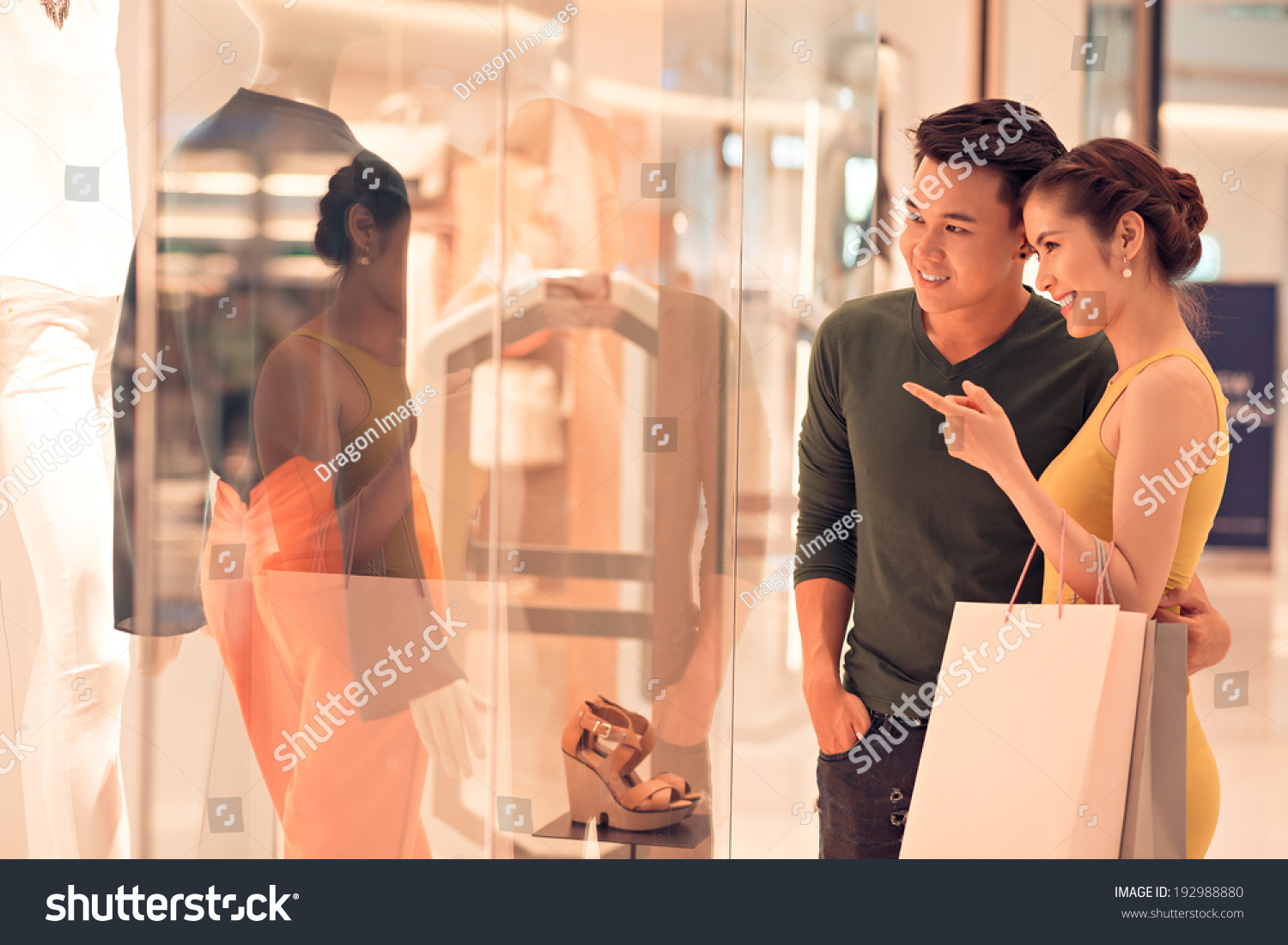 Young woman showing something in the shop window to her husband