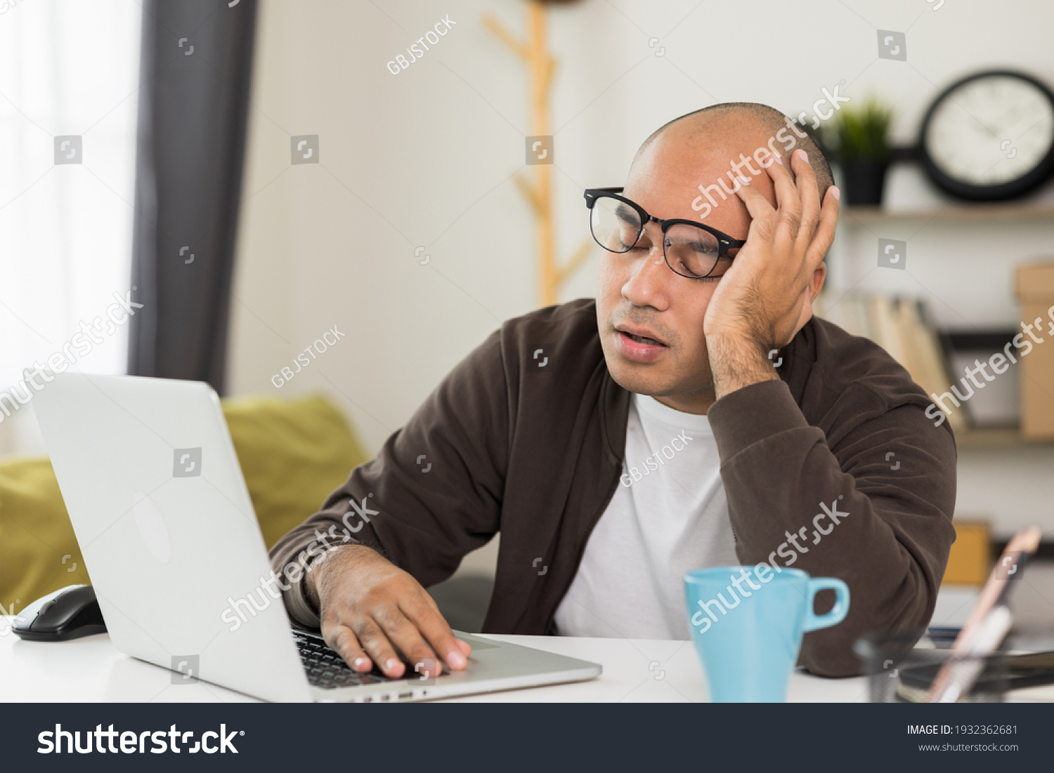 The young man was working in front of the laptop he was tired. And fell asleep on the desk He needs rest
