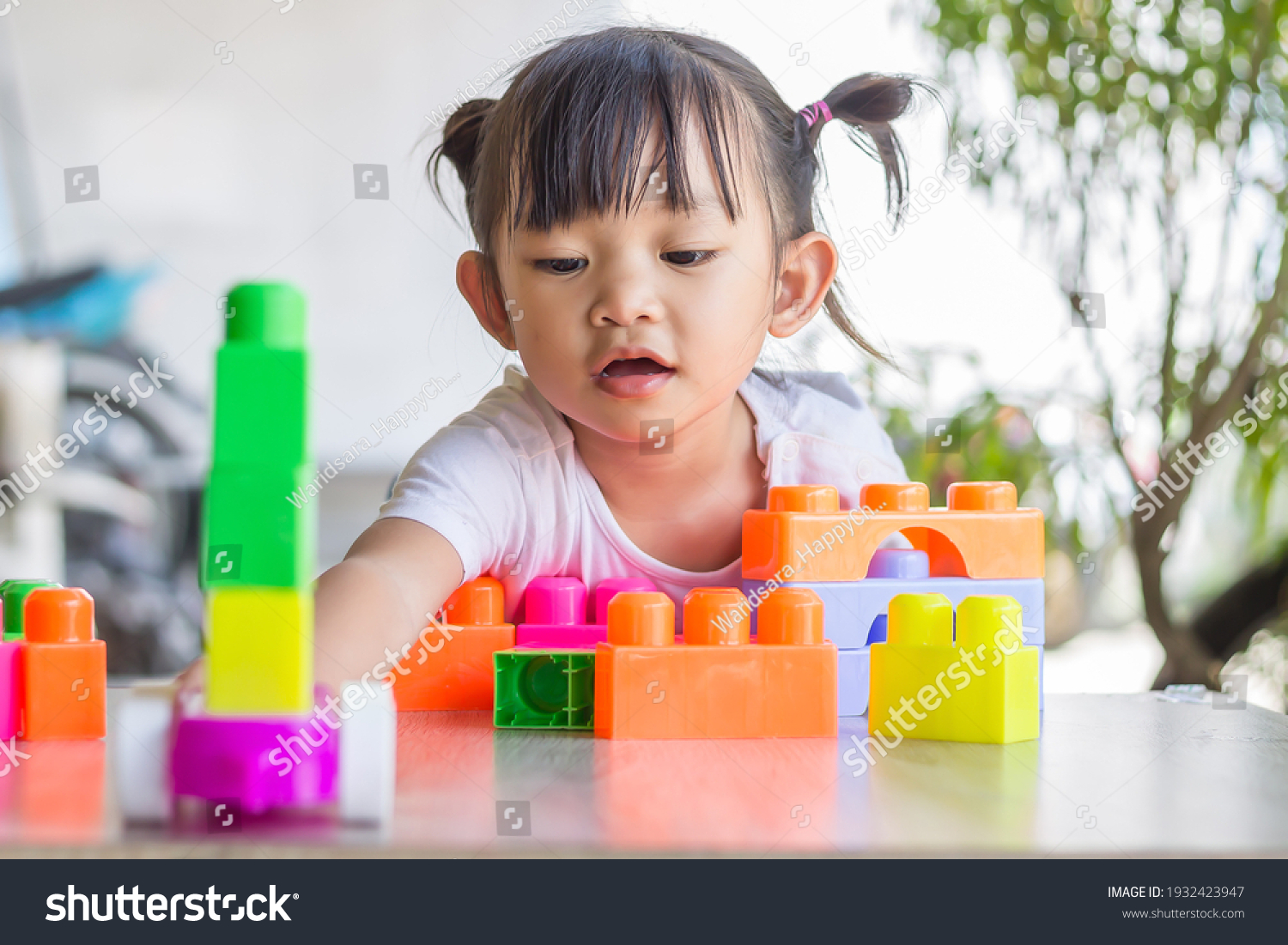 Portrait image of 3-4 toddler kid. Happy Asian child girl playing the plastic block toys. Learning and education concept. Smiling little baby.