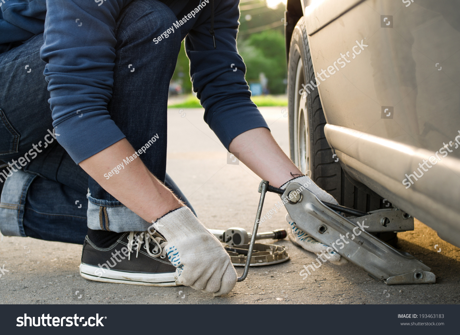 Man picks up a car jack to change a tire