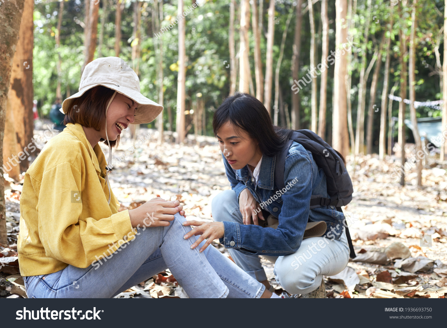 A tourist or female hiker is feeling a knee injury due to an accident accompanied by a companion nearby.