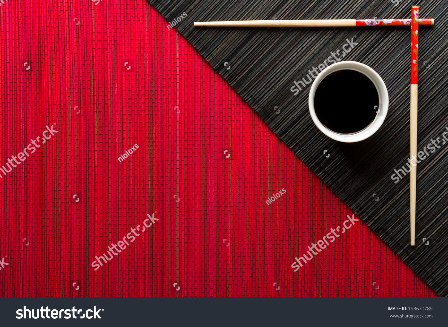 Chopsticks and bowl with soy sauce on bamboo mat