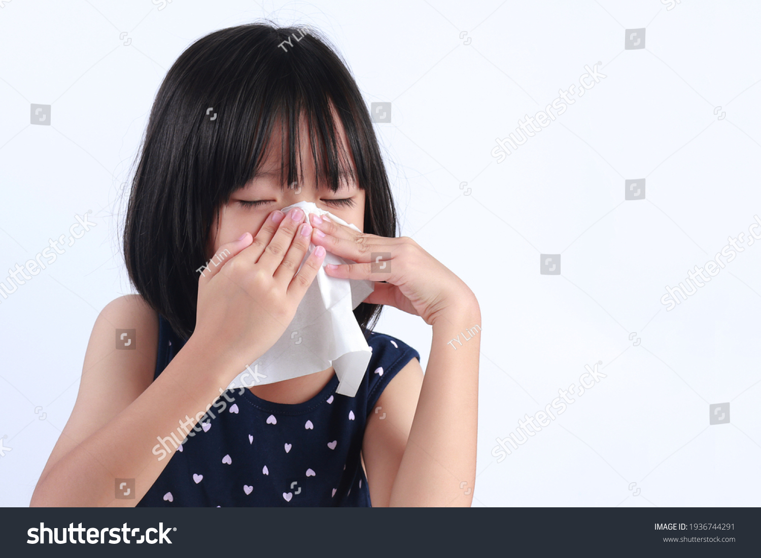 Sick little Asian girl wiping or cleaning nose with tissue isolated white background