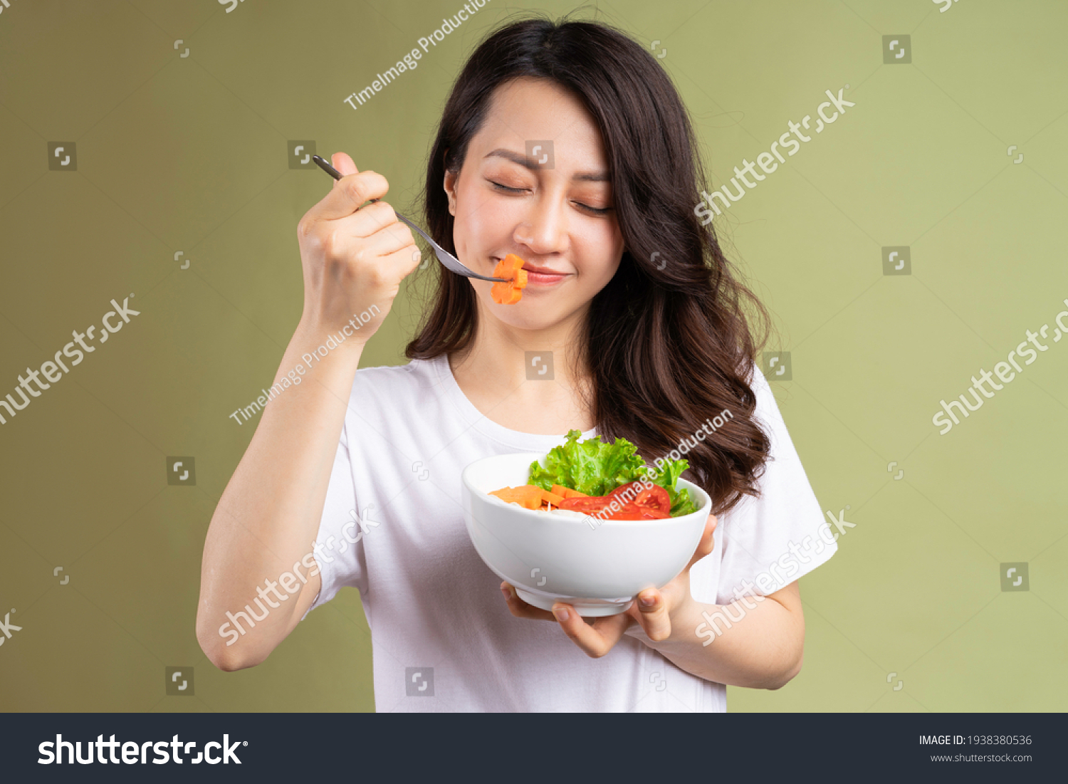 Cheerful young asian girl eating health food on background