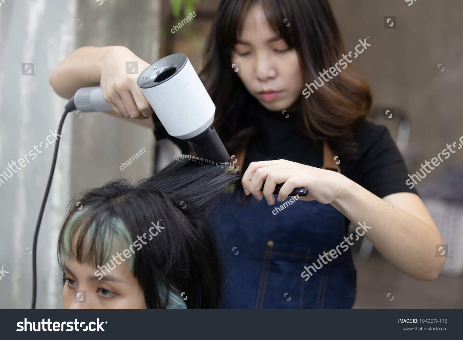 View of Asian Hairdresser Drying Women's Hair in Salon with a Hair Dryer