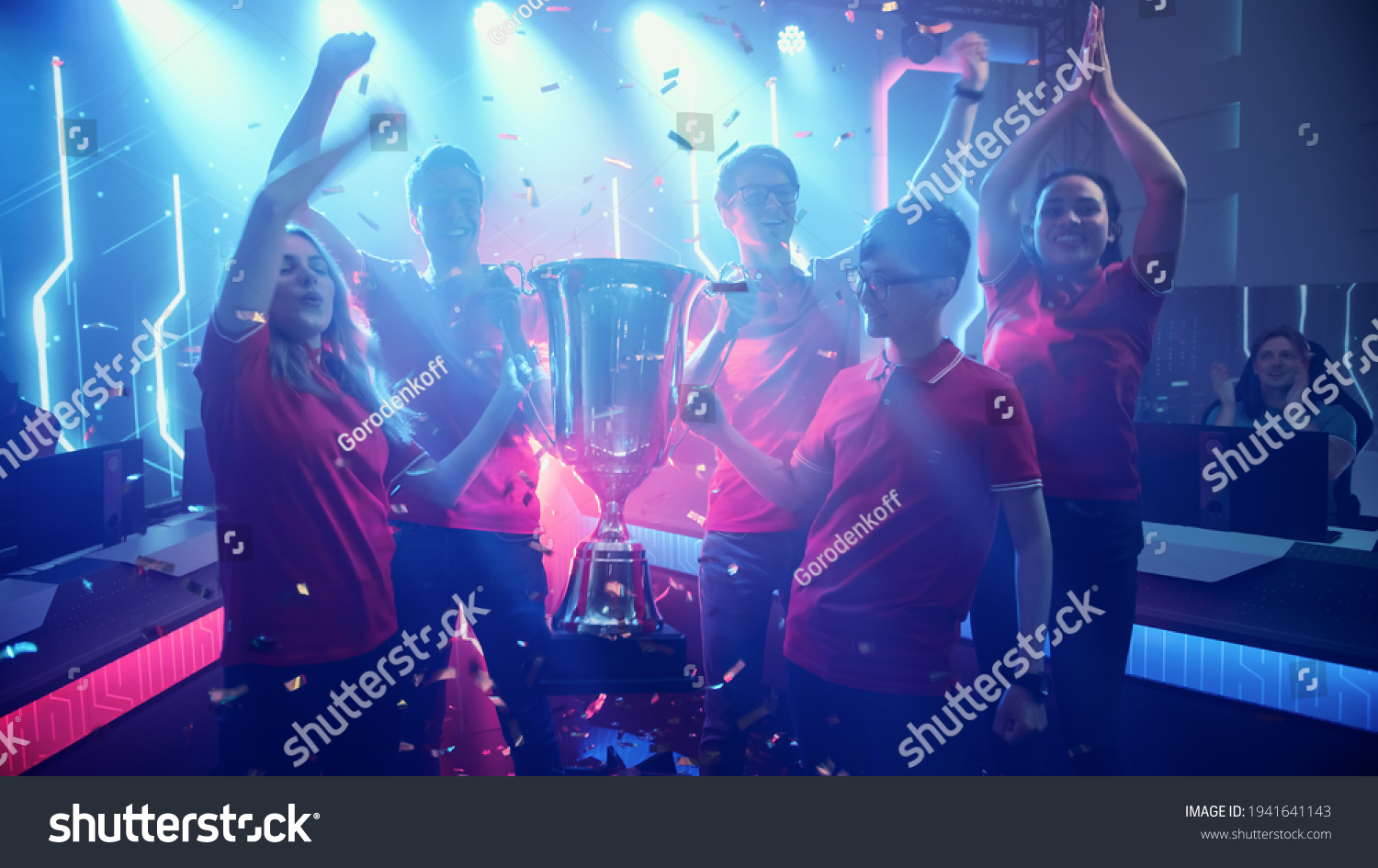 Diverse Esport Team Winner of the Video Games Tournament Celebrates Victory Cheering and Holding Trophy in Big Championship Arena. Cyber Gaming Event with Gamers and Fans.
