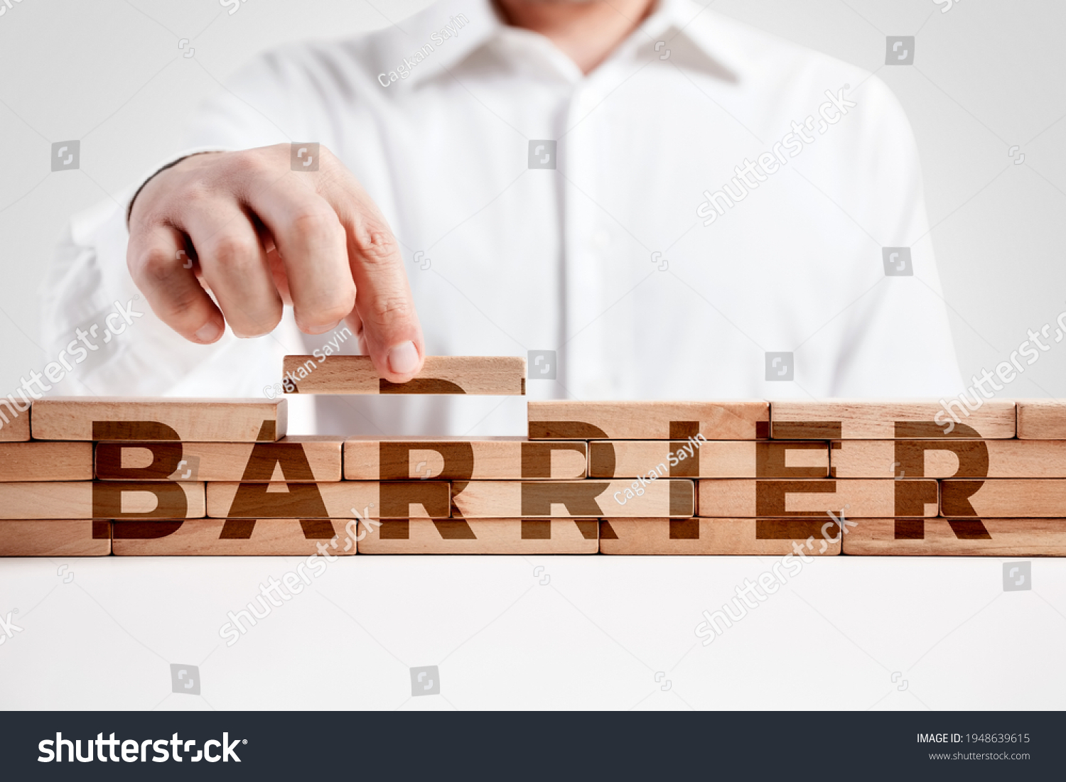 Businessman builds a structure of wooden blocks with the word barrier. Building a barrier concept. 