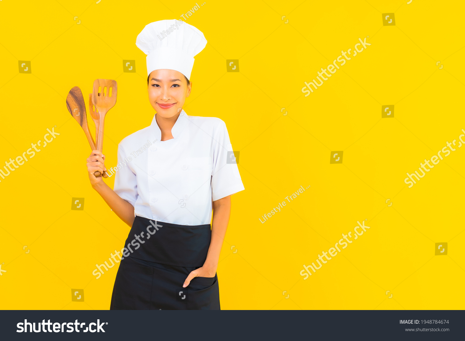 Portrait beautiful young asian chef woman with spatula on yellow isolated background