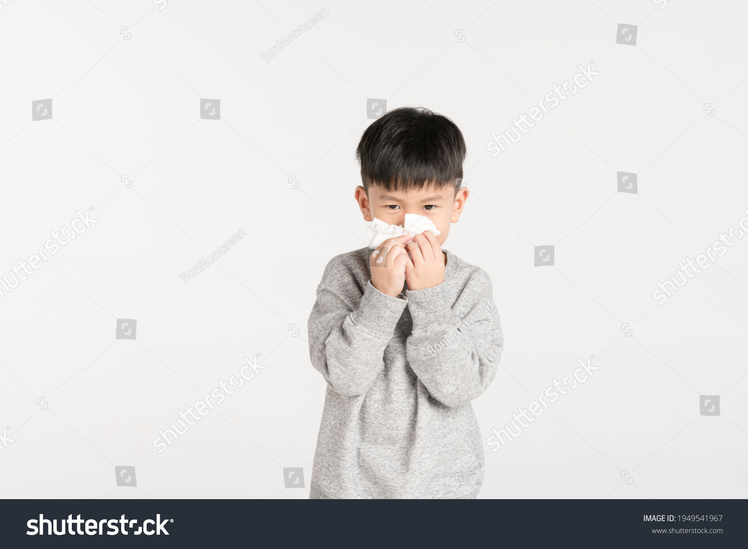 Asian boy about 5 year old holding tissue paper while sneezing or blowing his nose