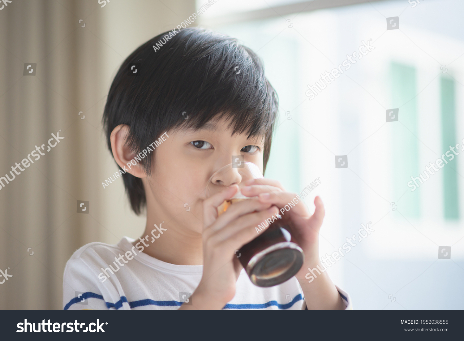 Little asian boy drinking soft drink cola soda