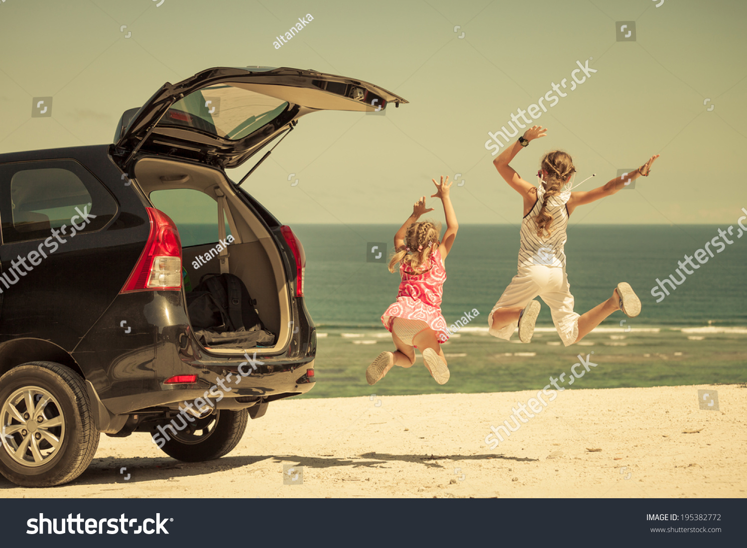 two sisters standing near a car on the beach