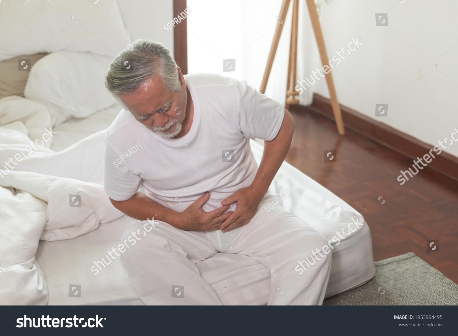Asian Elderly man Stomachache in bedroom.