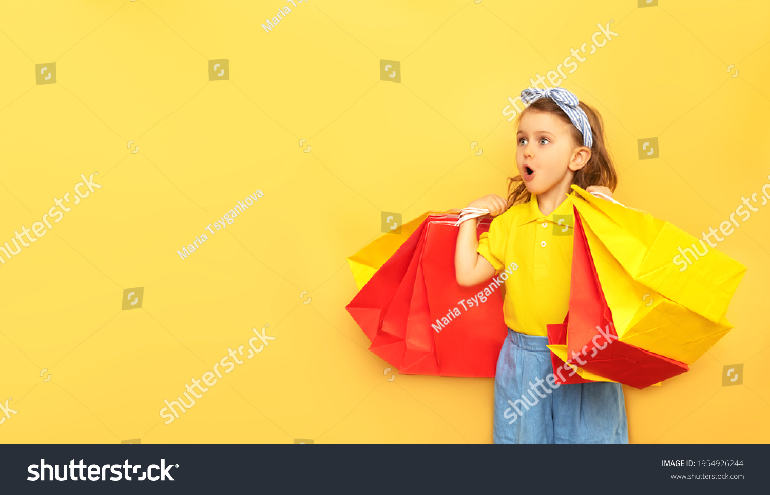 Surprised child girl in summer clothes hold package bag with purchases isolated on yellow background studio. Shopping discount sale concept. Mock up copy space banner. Black friday