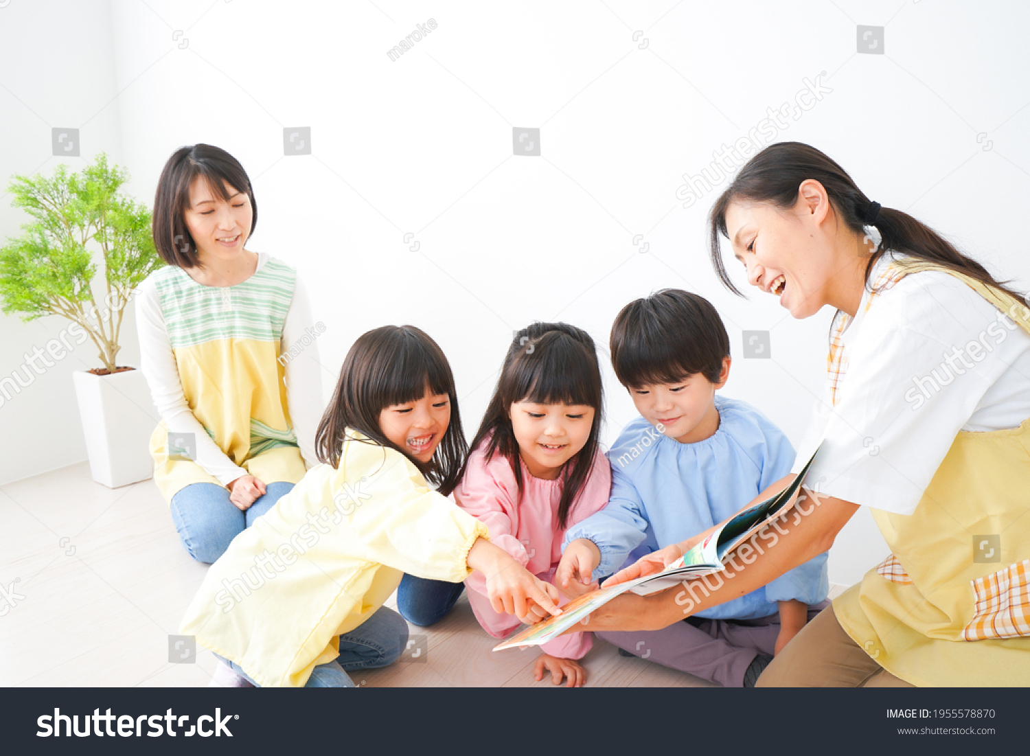 Nursery teacher and children reading a picture book