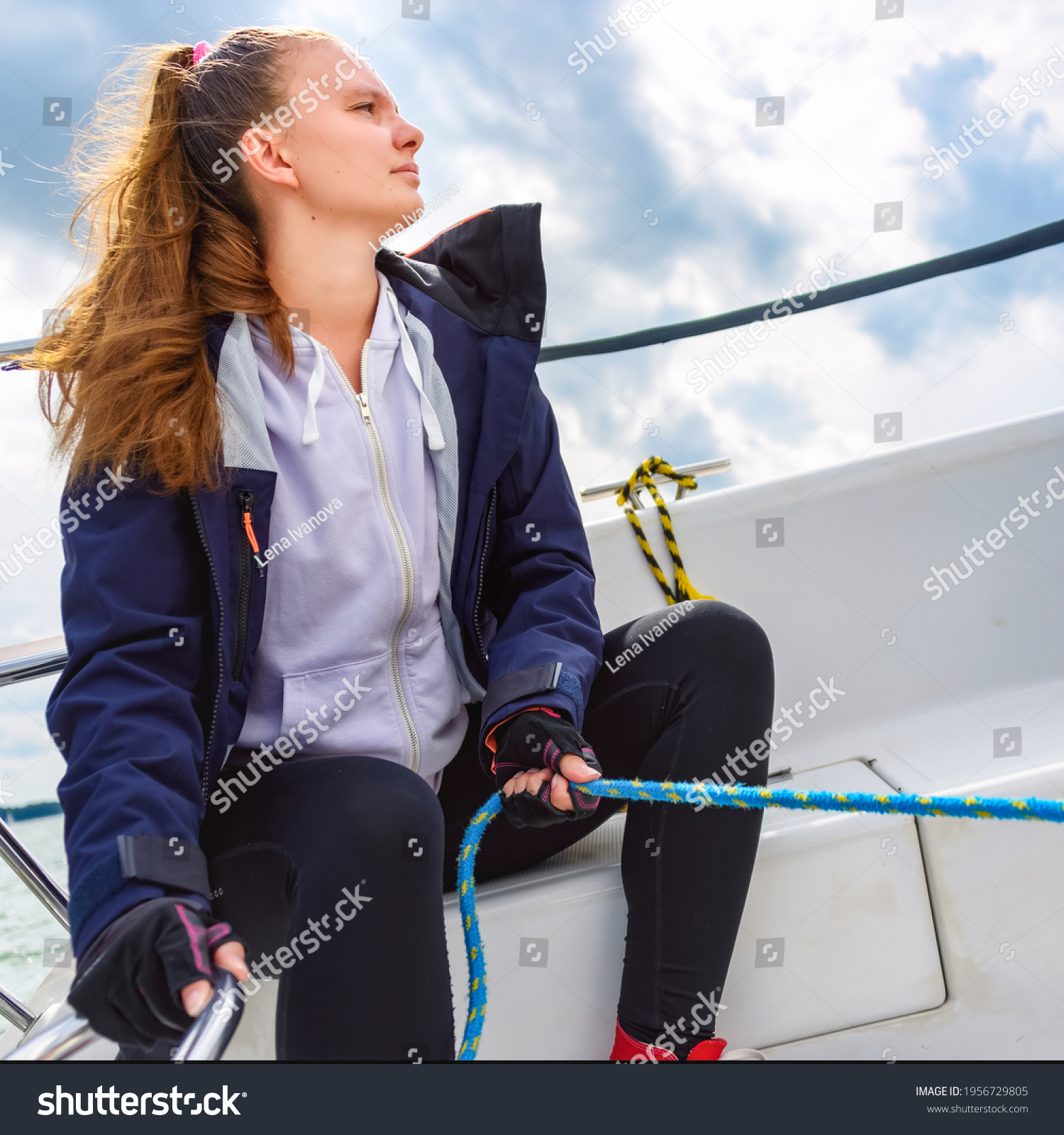 youngwomansteeringasailboatsailingonalakesummervacationscruise