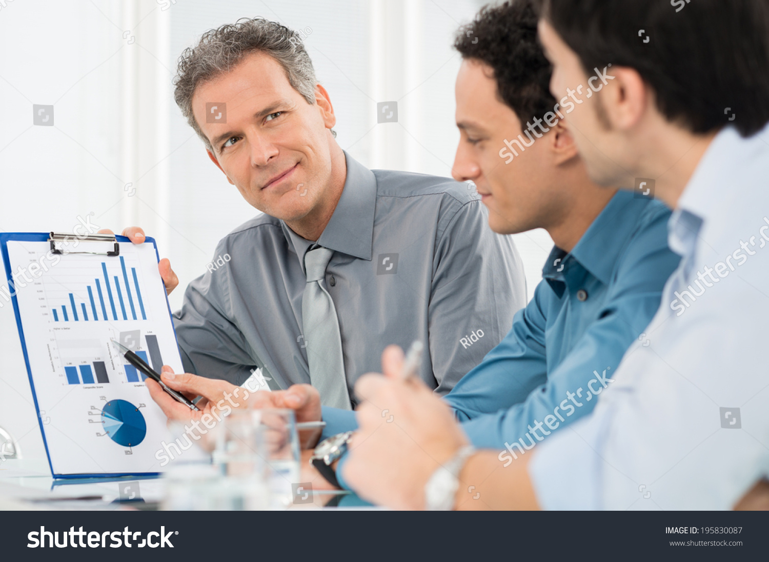 Portrait Of Mature Businessman Showing Annual Report Graph To His Colleague
