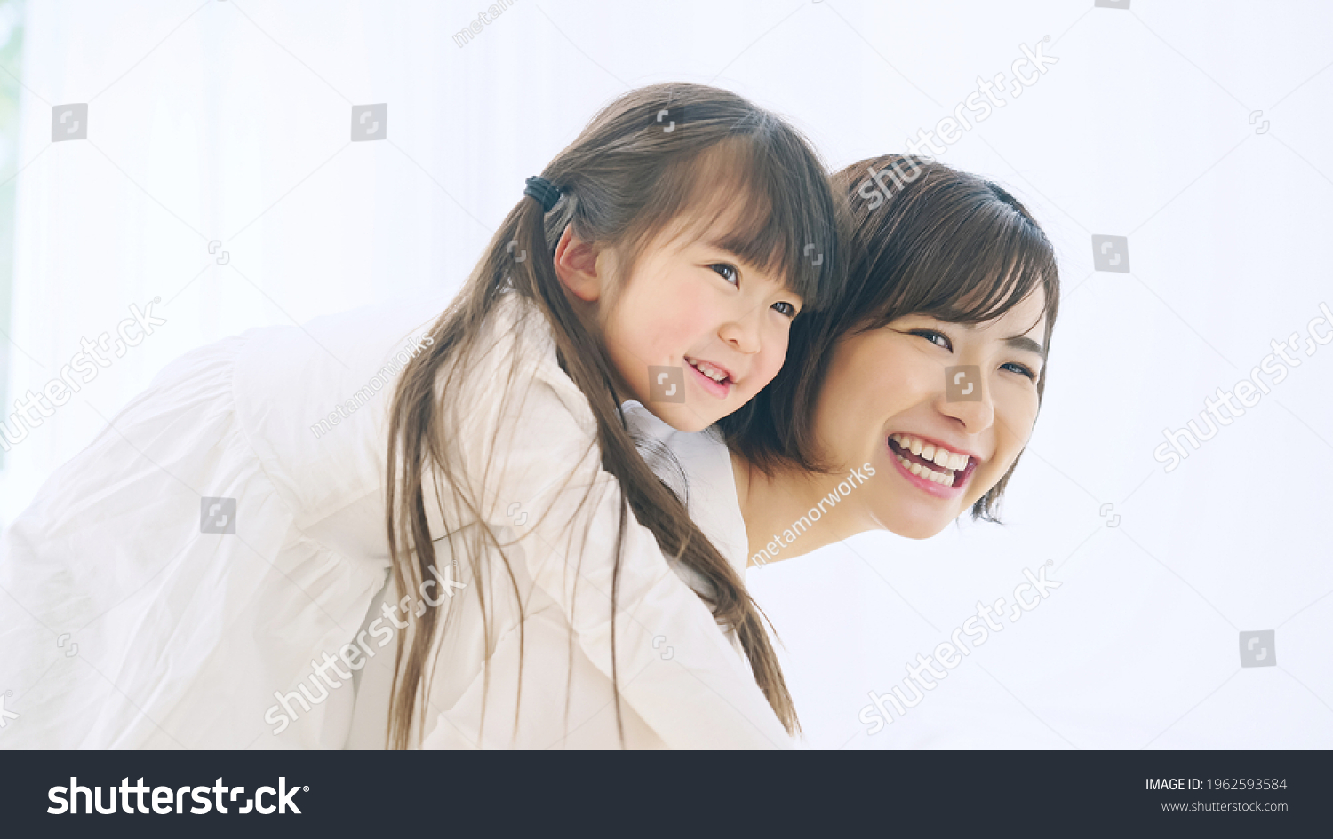Young asian woman piggybacking a little girl.