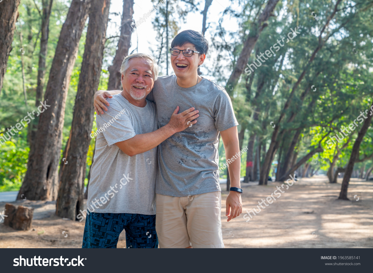 Happy Asian senior father and adult son do sport exercising on the beach together in summer morning. Healthy man with retirement elderly father relax and enjoy outdoor lifestyle activity on vacation