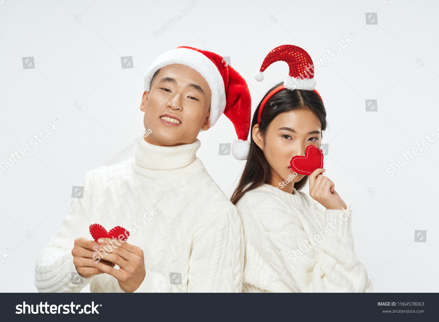 cheerful young couple of asian appearance with hearts in hands holiday christmas