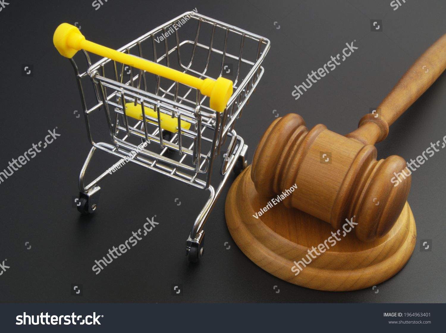 Wooden judge gavel and shopping cart on black table. Commercial law and consumers rights concept.