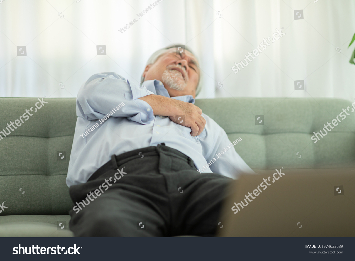 Emergency of Asian Elderly senior man sudden heart attack so pain on chest and illness with diabetes symptoms on sofa due working alone and need Urgently help at home Elderly care concept