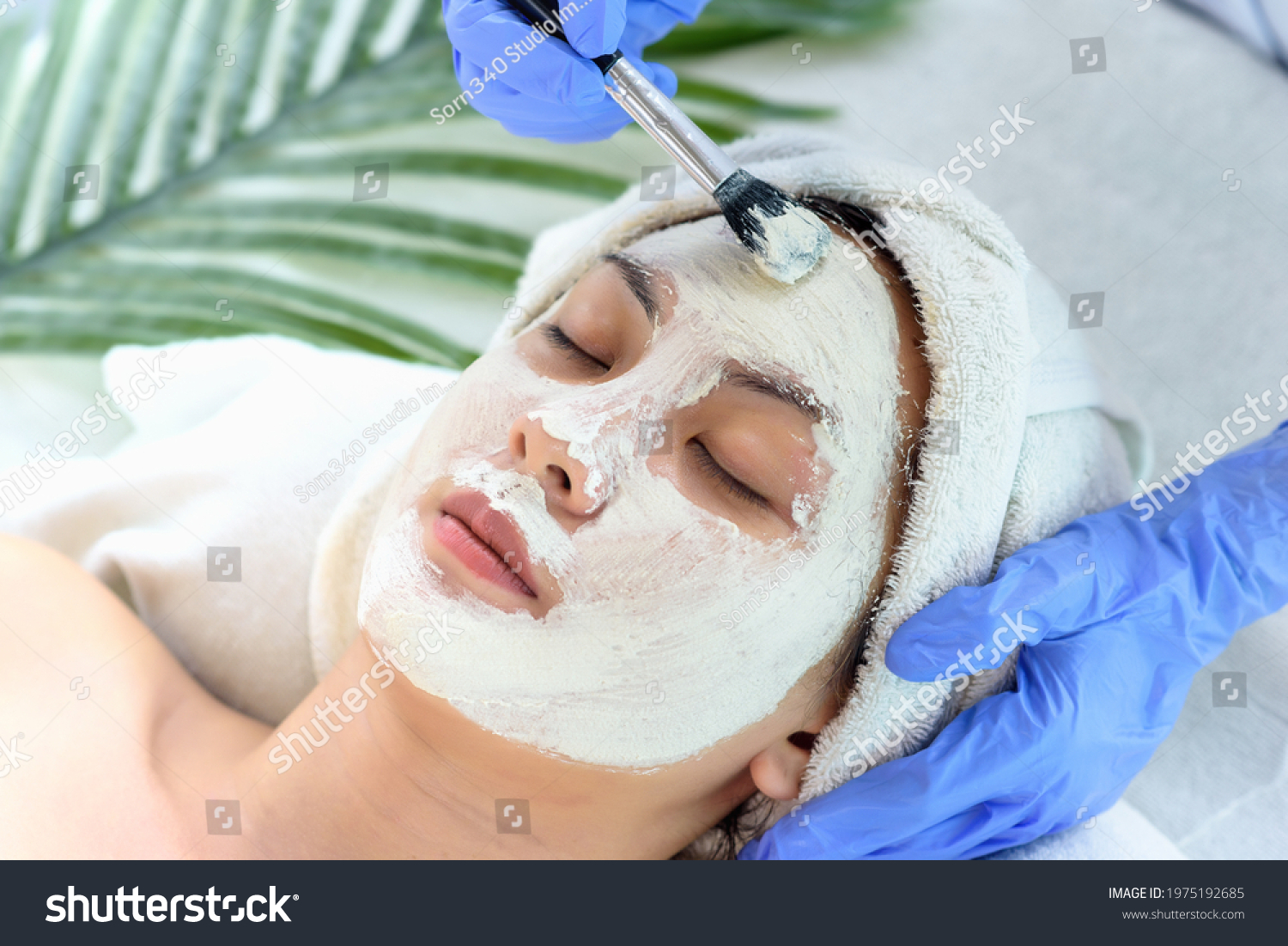 Young Asian Women getting facial care  Facial masks  and spa beauty treatment for soft smooth silky skin by beauticians at spa salon. Beauty skincare concept