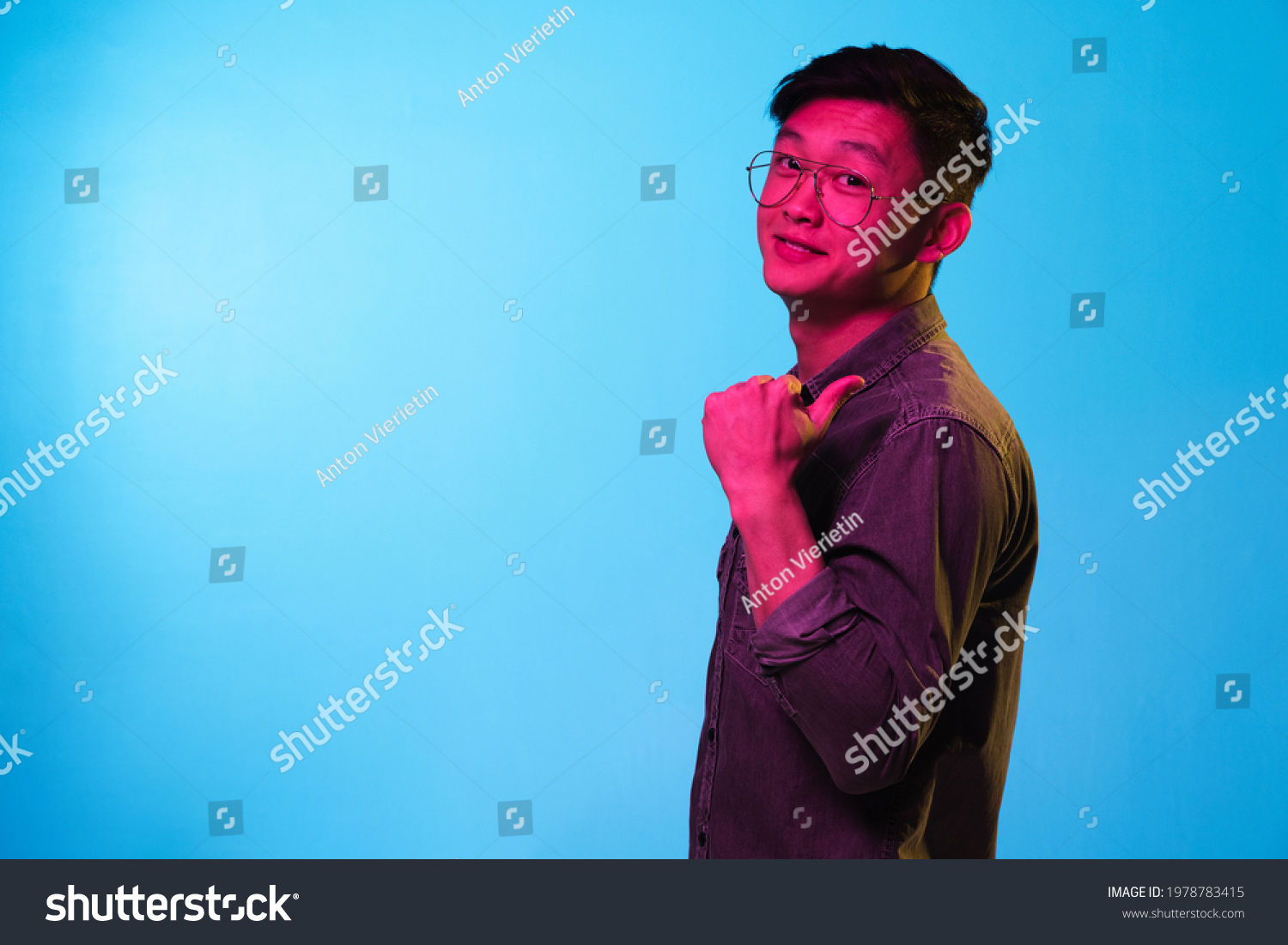 Portrait of Asian young man isolated over blue background in neon light.